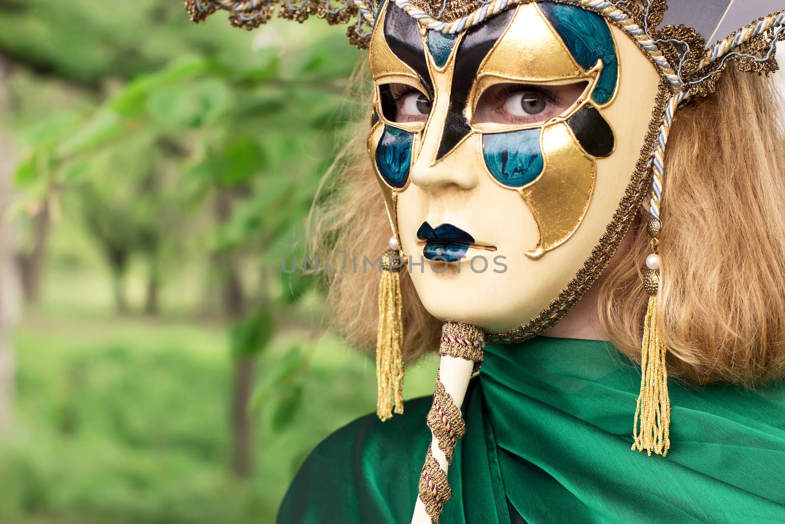 Beautiful woman in carnival mask over foliage background by deamles