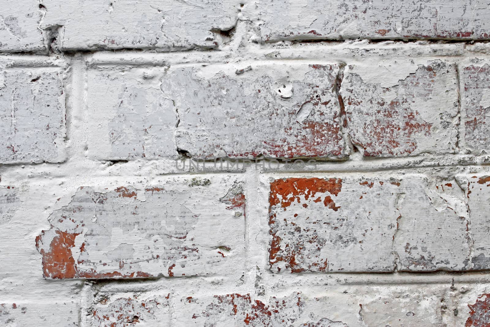 Fragment of old brick walls covered with many lime layers