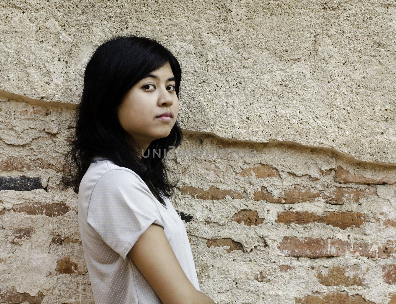 Proud asian woman looking at you over brick background