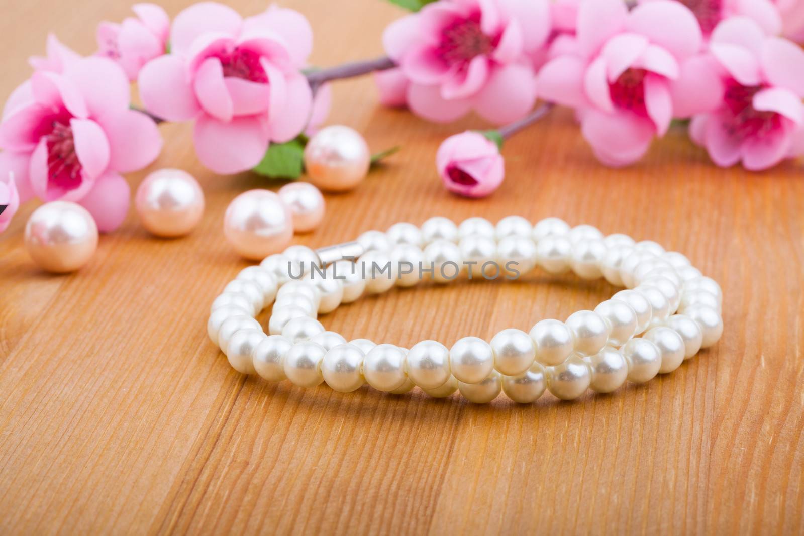 pearl bangles, with pink flower on wooden background