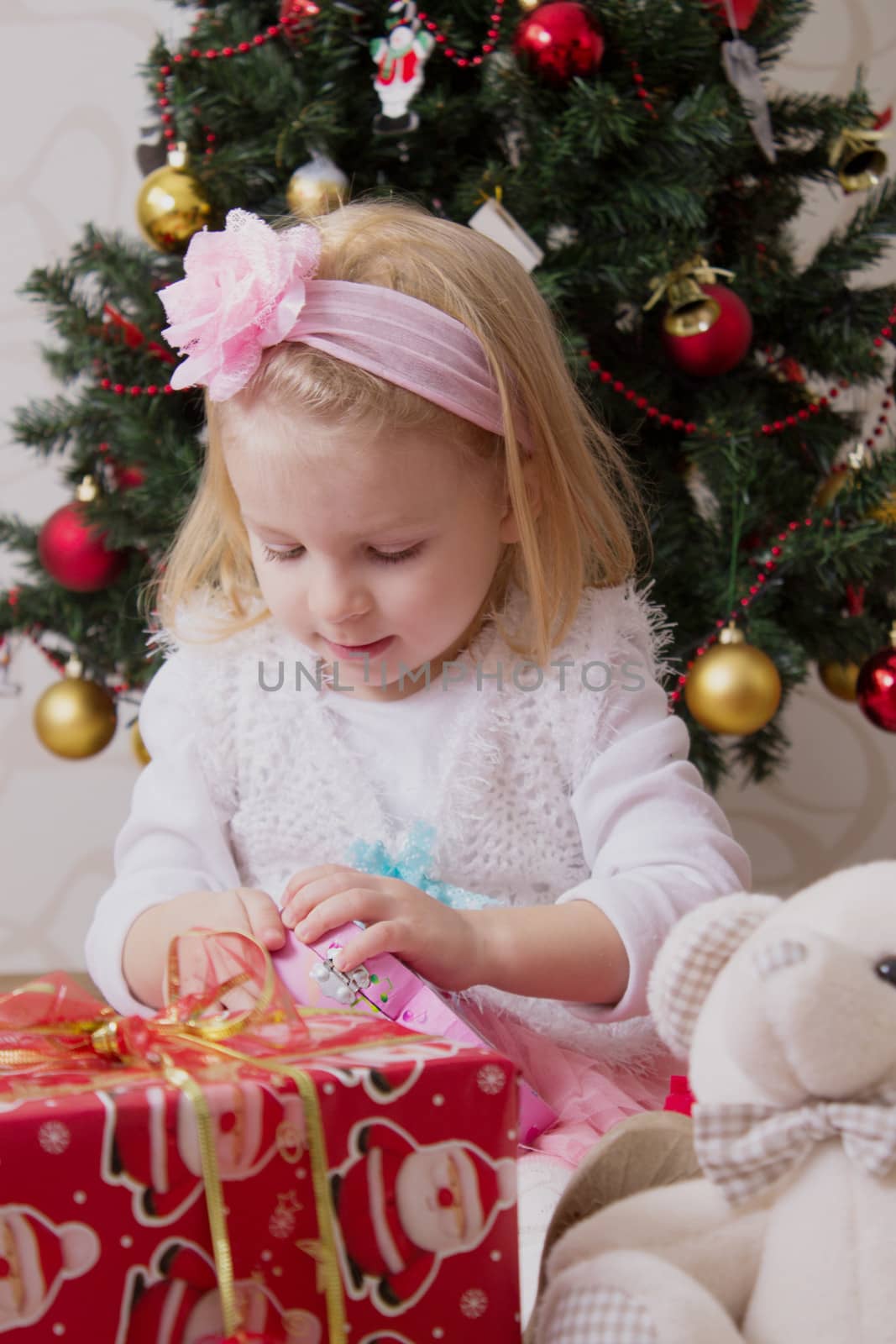 Girl in pink under Christmas tree holding giftbox by Angel_a