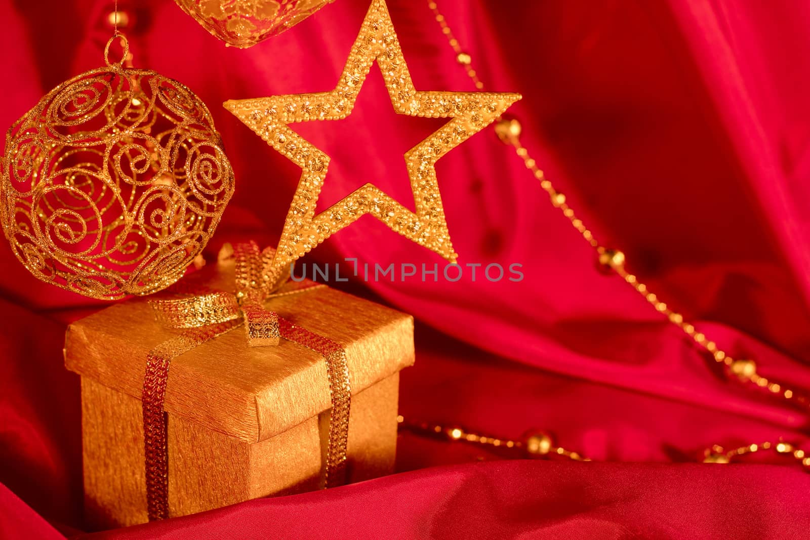 Golden christmas decoration and gift on red fabric background
