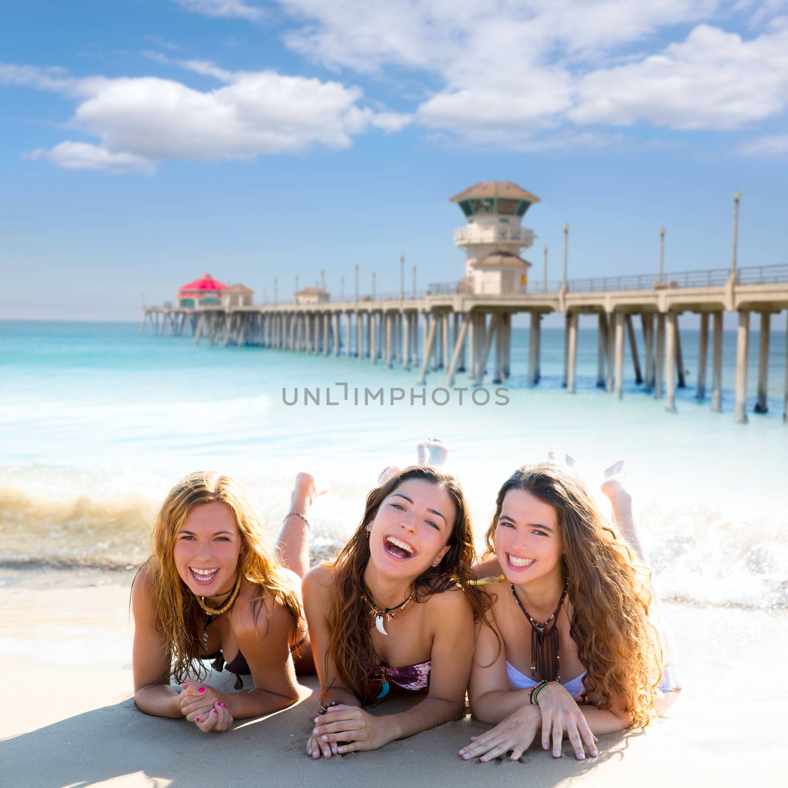 happy three friends girls lying on beach sand smiling by lunamarina