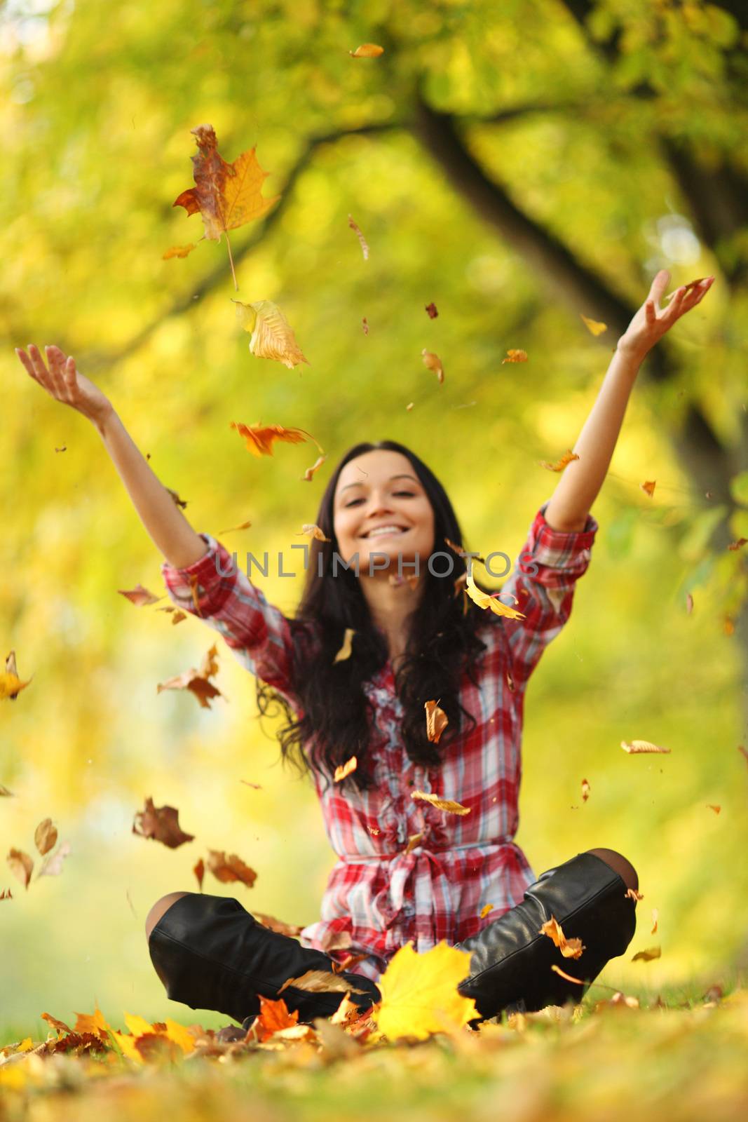 woman drop up leaves in autumn park