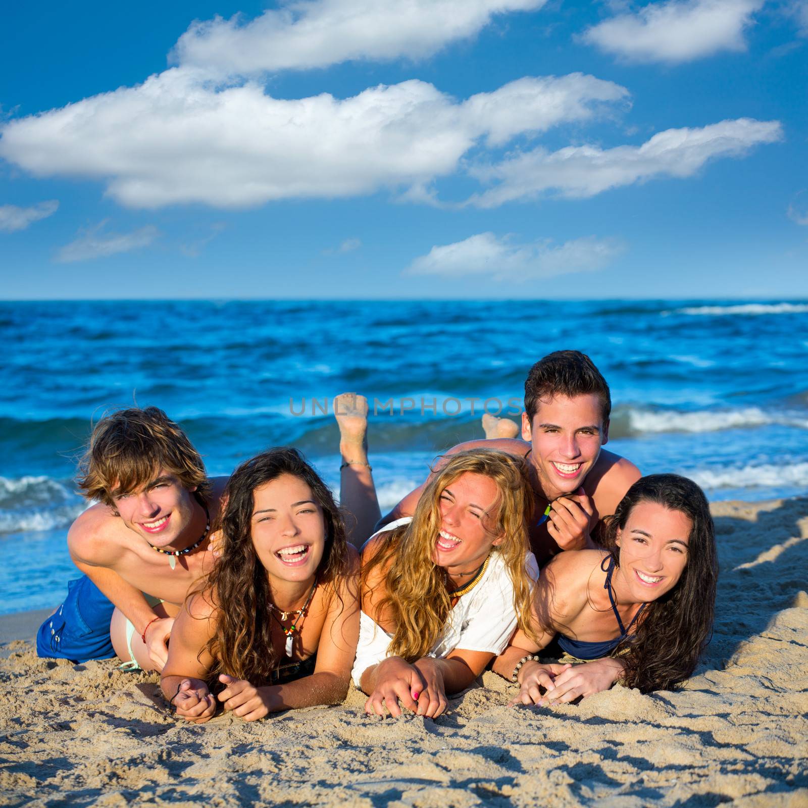 Boys and girls teen group having fun happy on the blue beach sand