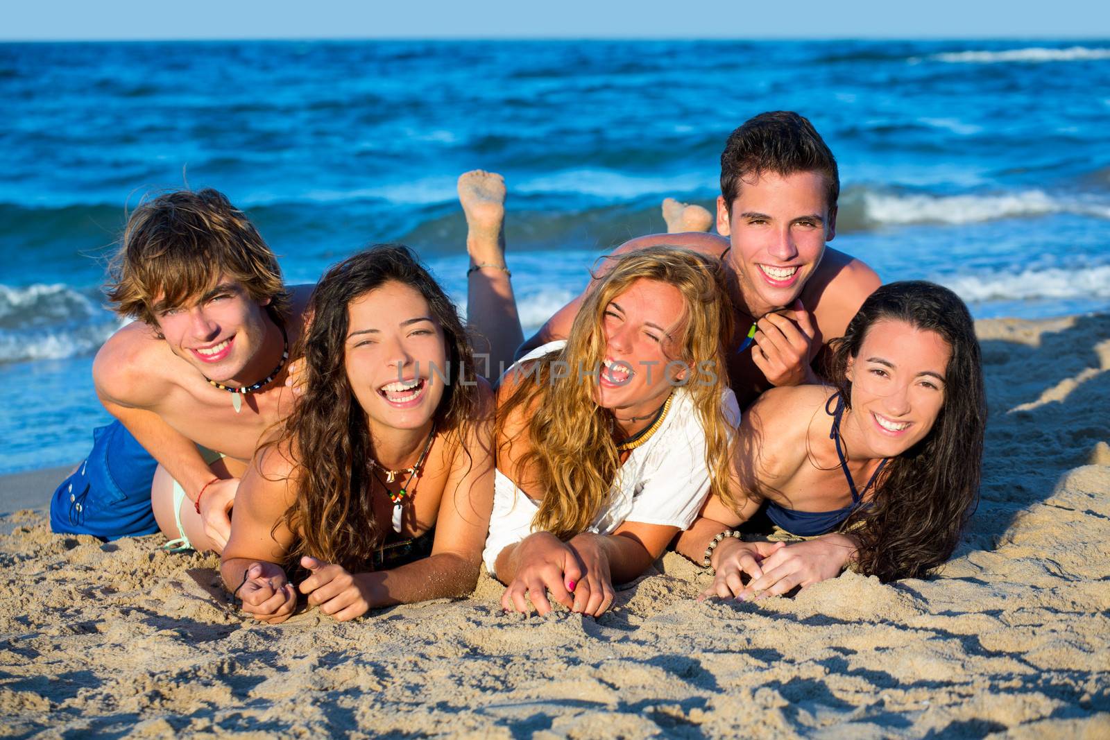 Boys and girls teen group having fun happy on the blue beach sand