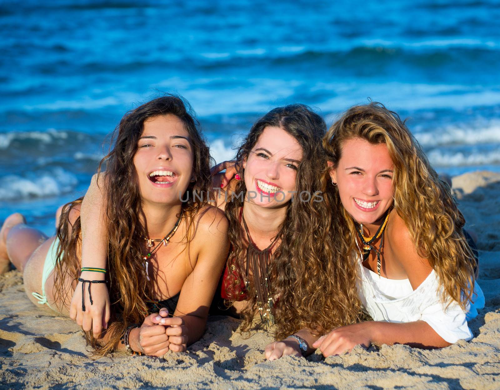 Girls friends having fun happy lying on the beach by lunamarina