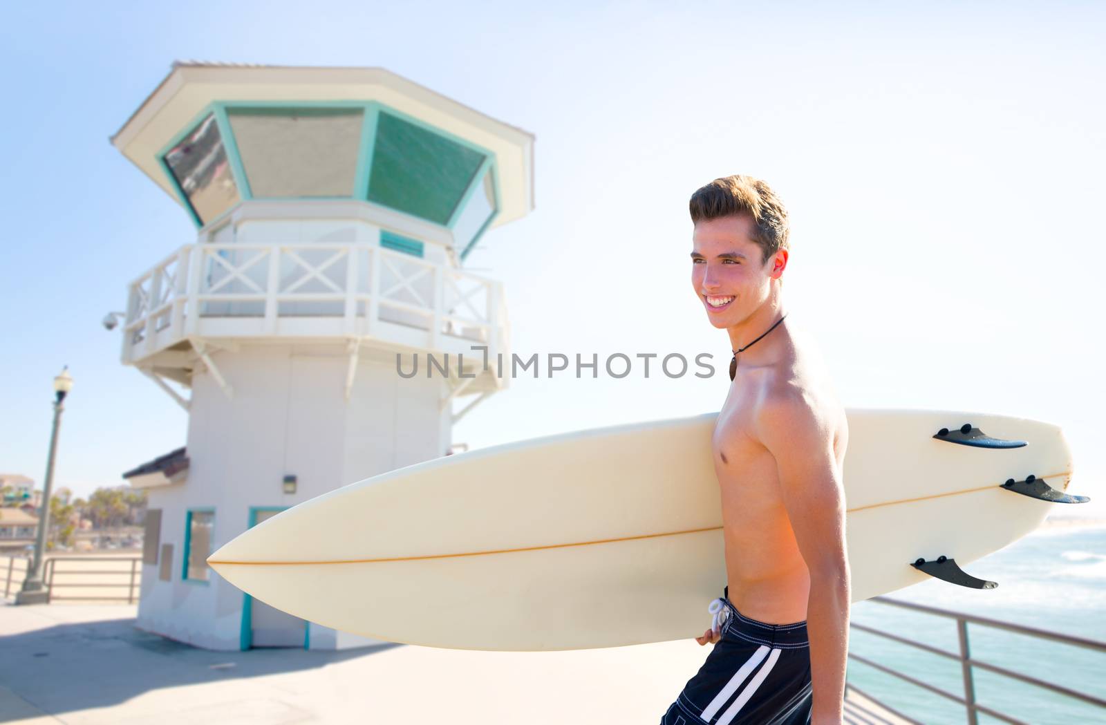 Surfer boy teenager with surfboard in Huntington beach pier California