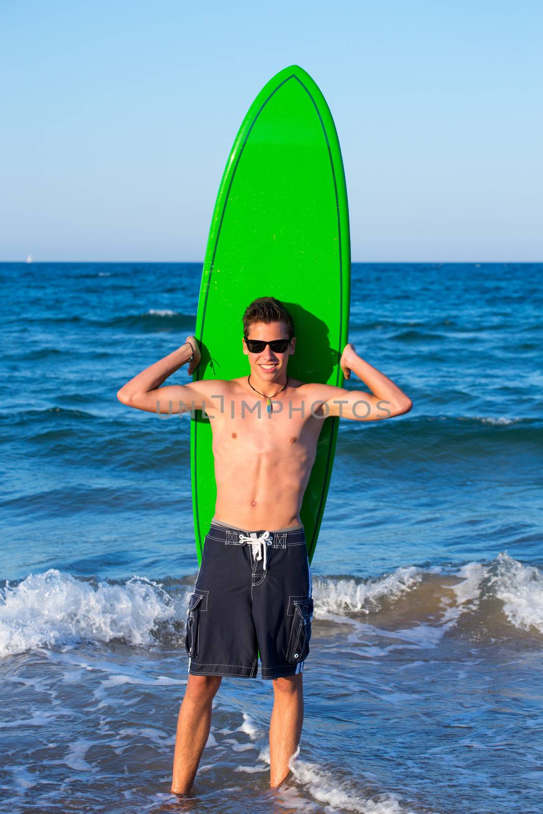 Boy handsome teen surfer holding surfboard in the blue beach