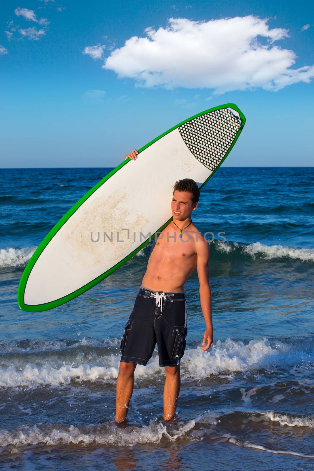 Boy handsome teen surfer holding surfboard in the blue beach