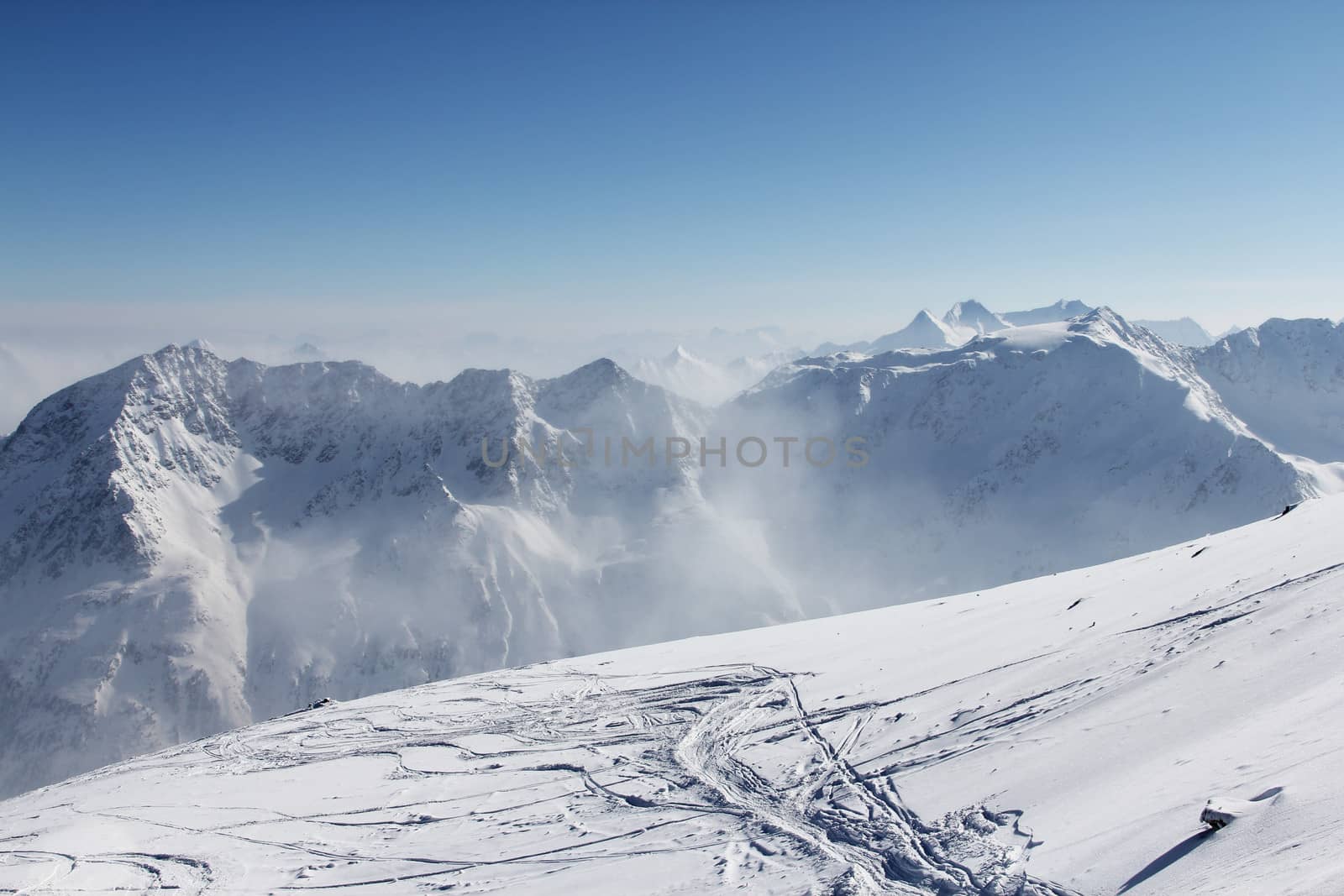 Ski traces on snow in alps under blue sky