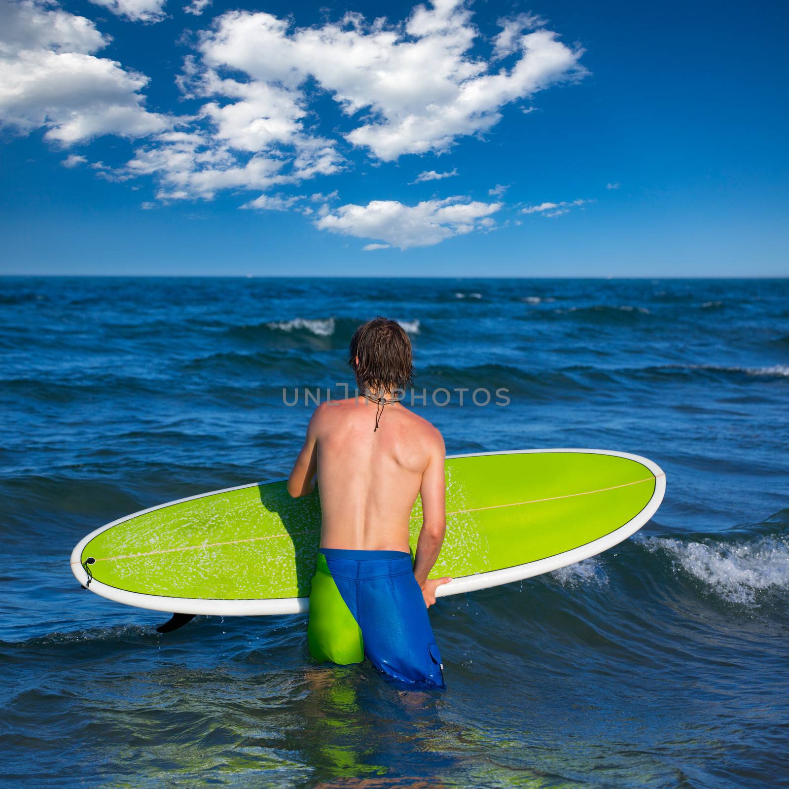 boy surfer waiting for the waves on the beach by lunamarina