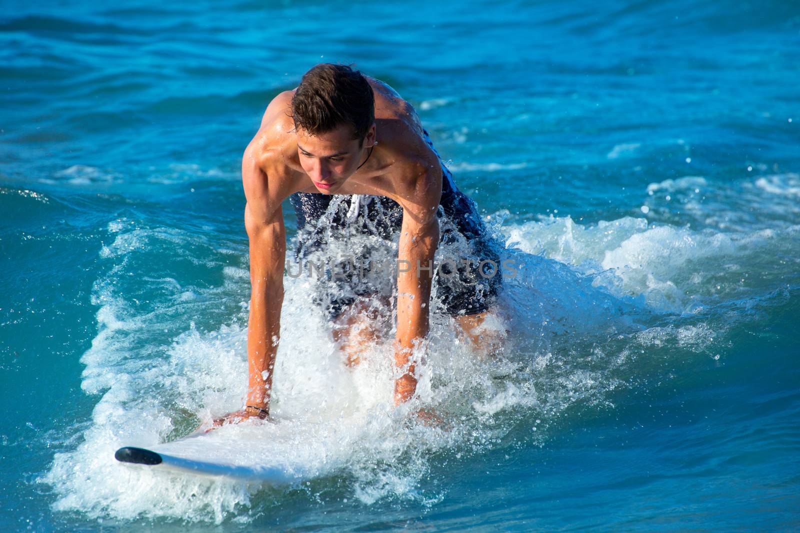 Boy surfer surfing waves on the beach by lunamarina