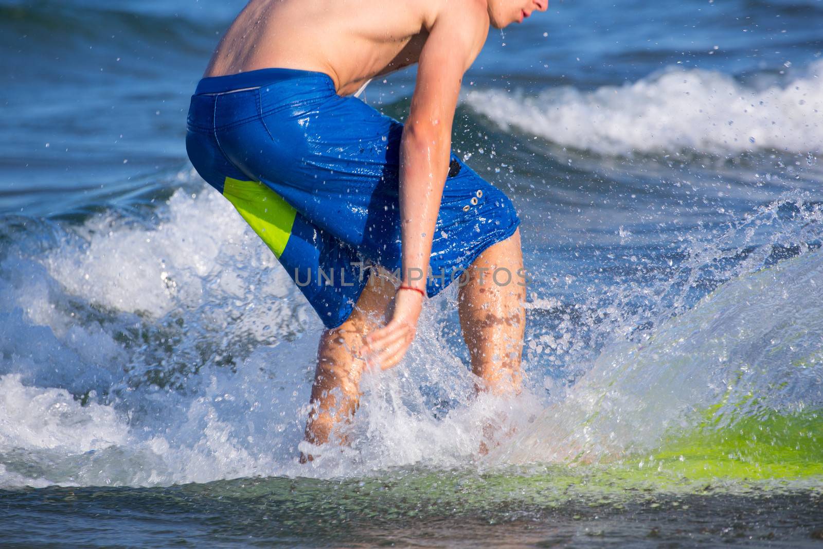 Boy surfer surfing waves on the beach enjoying fun