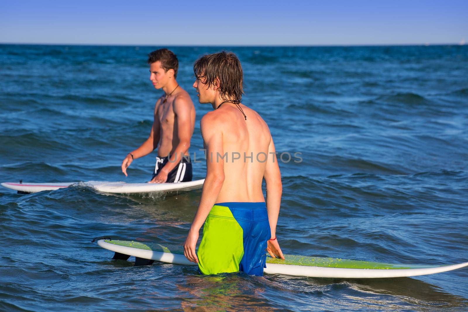 boys surfers waiting for the waves on the blue beach