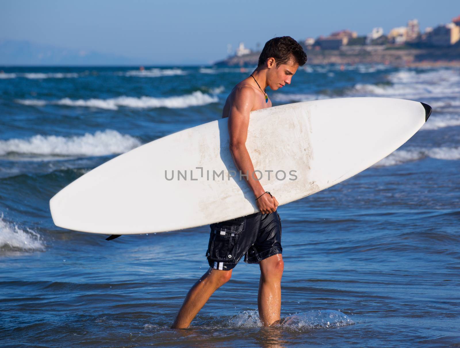 boy surfer holding surfboard caming out from the waves by lunamarina