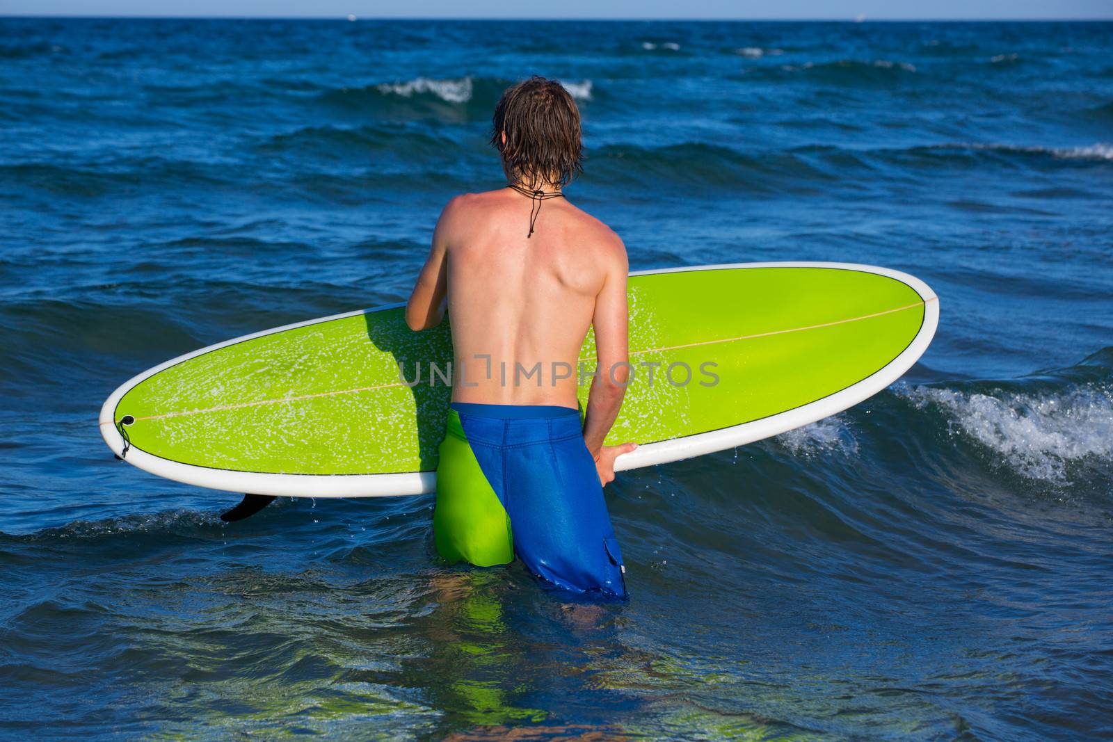 boy surfer waiting for the waves on the blue beach