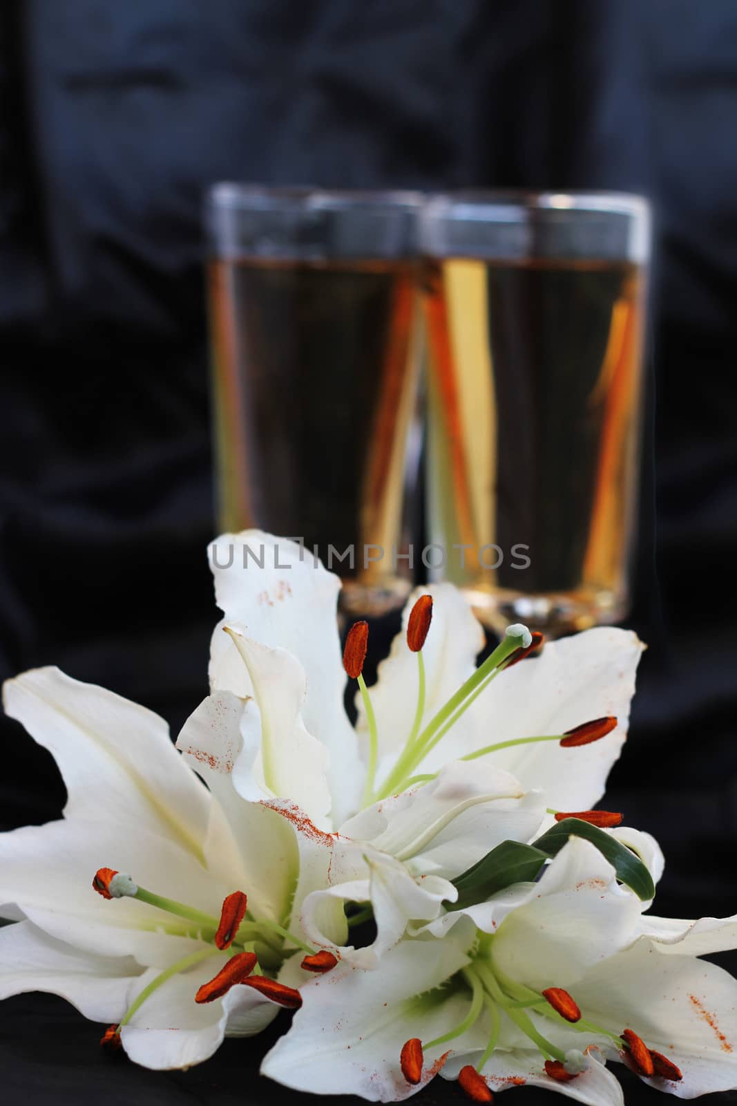 Glasses with wine and lily flower on black silk