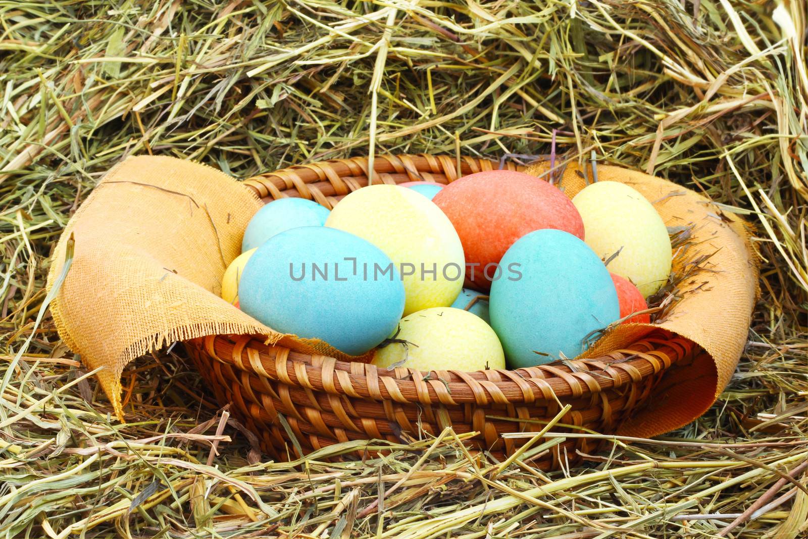 Basket of colored easter eggs on hay