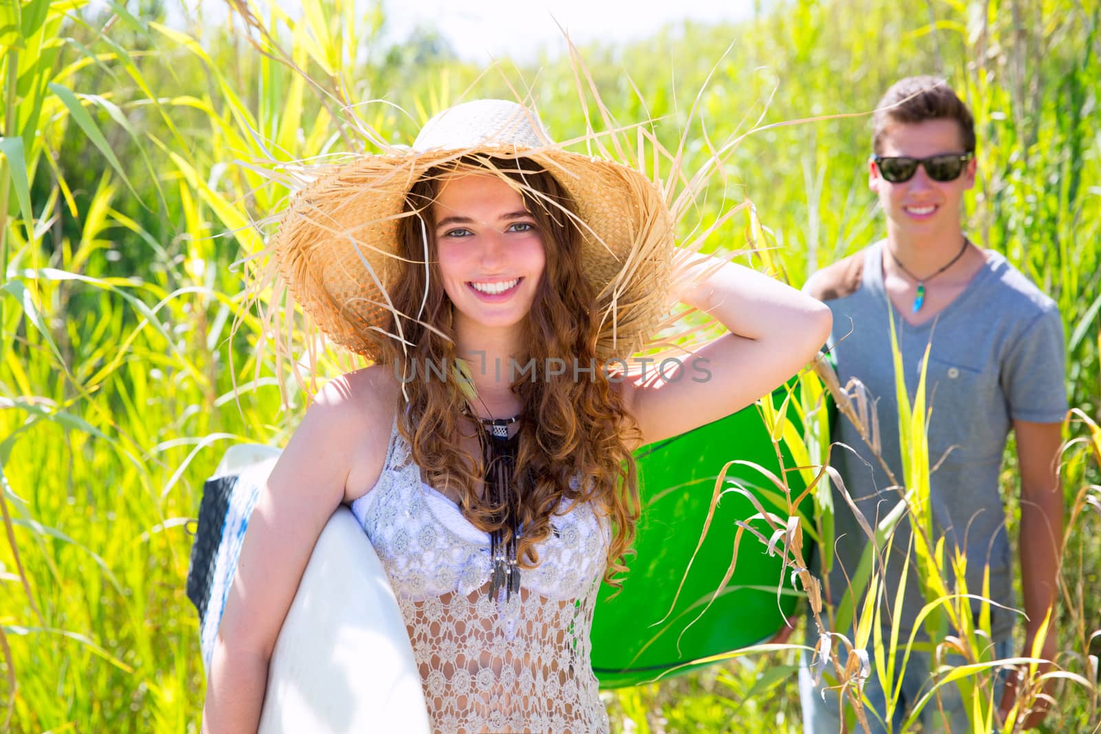 Girl surfer with beach hat walking with surfboard and her friend