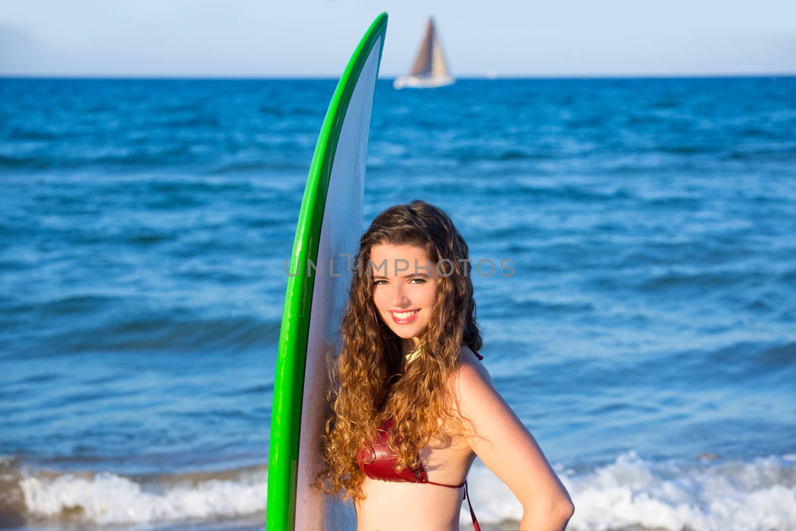 Young surfer girl holding surfboard in a beach by lunamarina
