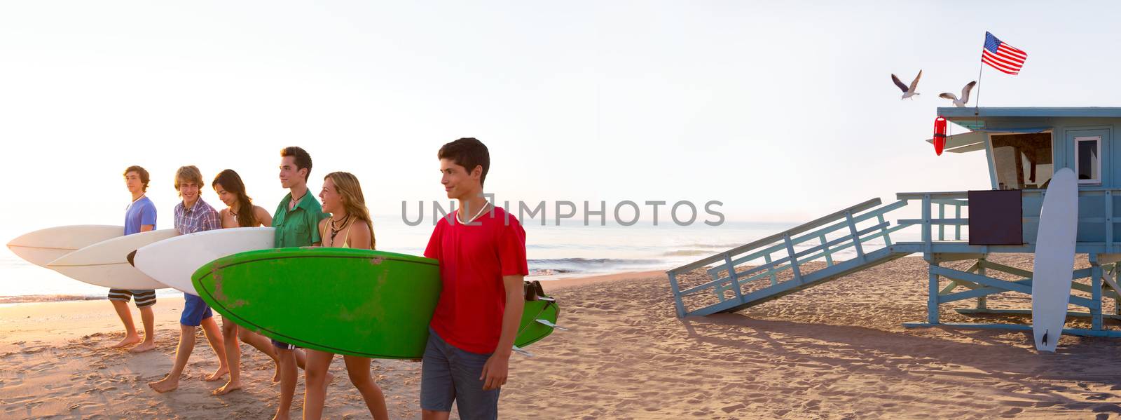 Surfer teenagers boys and girls walking on California beach at Santa Monica