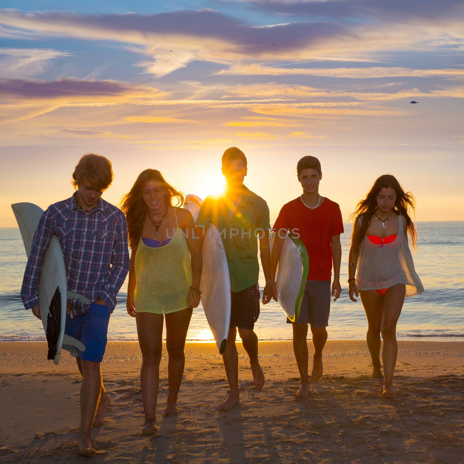 Surfers boys and girls group walking on beach by lunamarina