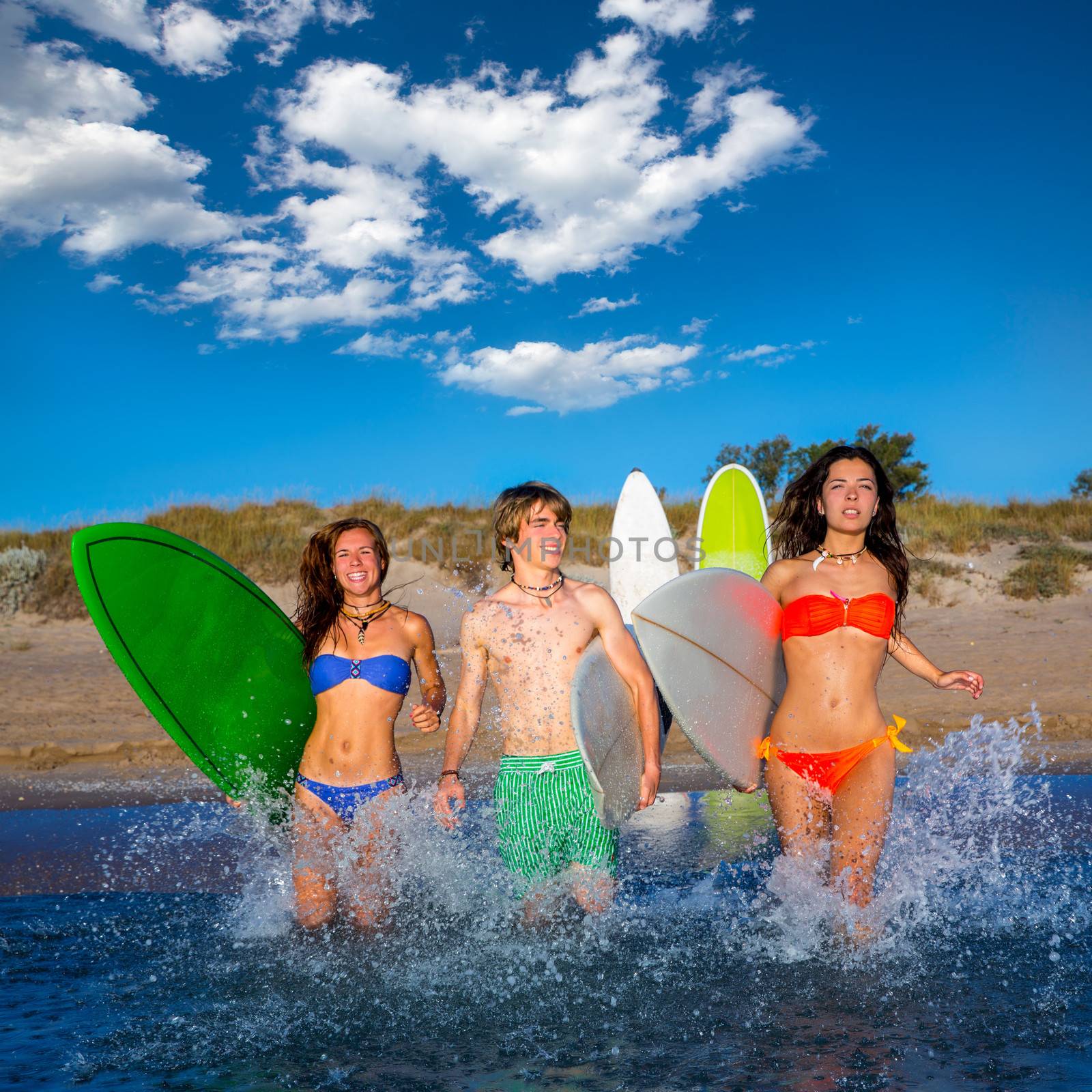 Teenager surfers group running beach splashing by lunamarina