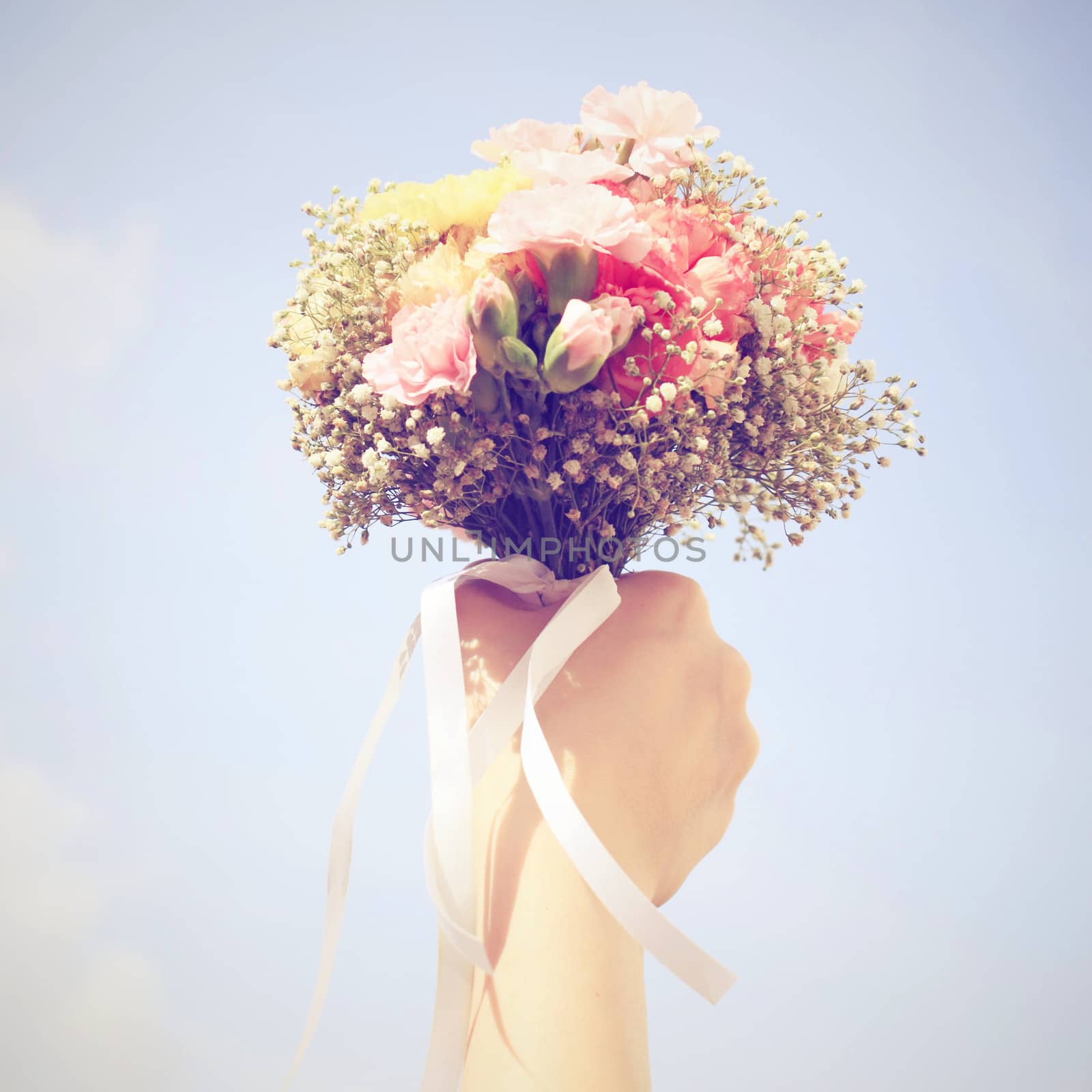 Bouquet of flower in hand and blue sky with retro filter effect