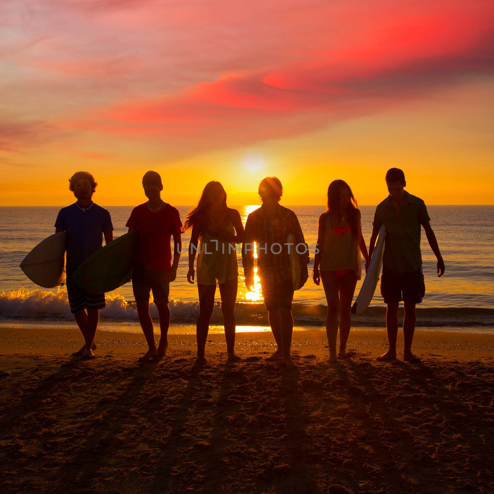 Surfers boys and girls group walking on beach by lunamarina