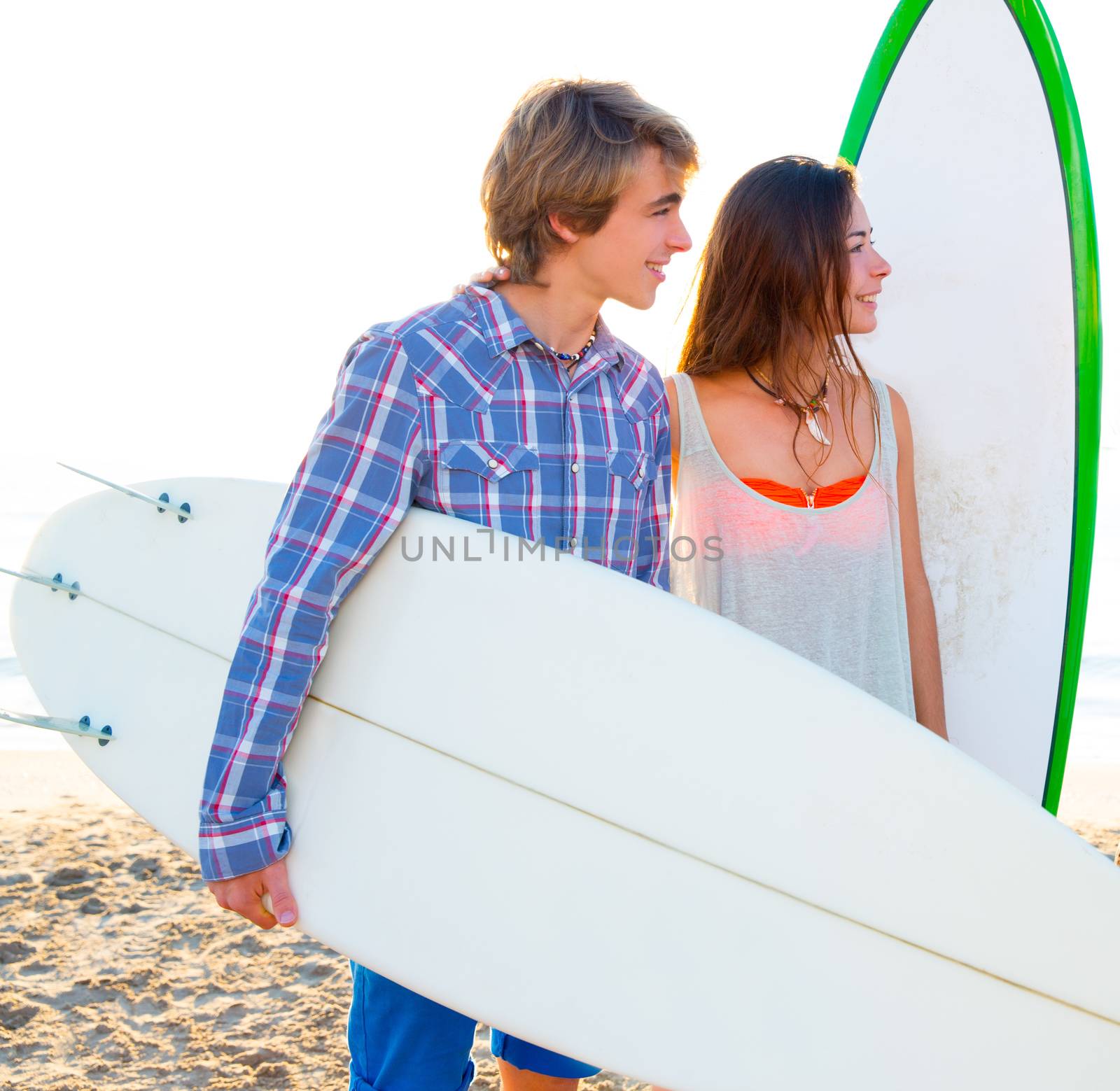 Teen surfer couple on beach shore with surfboards high key