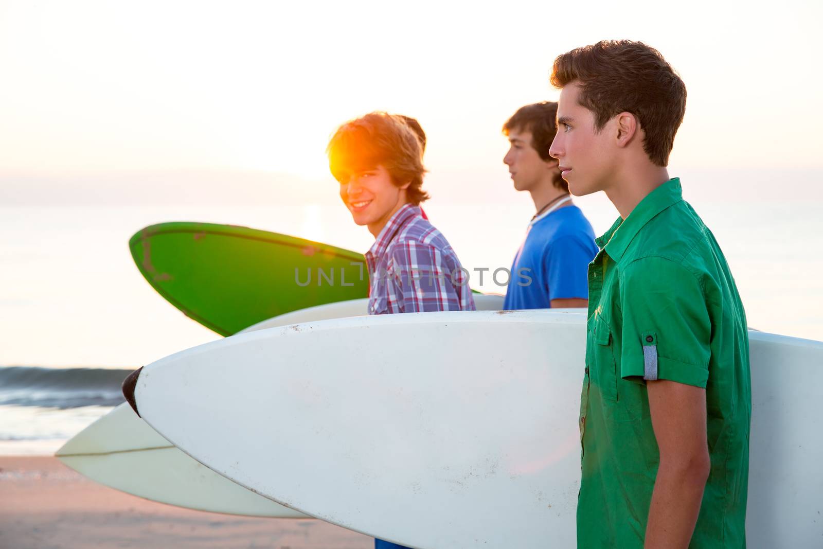 Surfer teen boys group walking at beach shore on sunshine or sunset