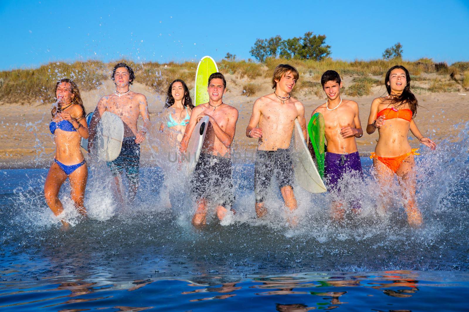 Teen surfers group running beach splashing by lunamarina
