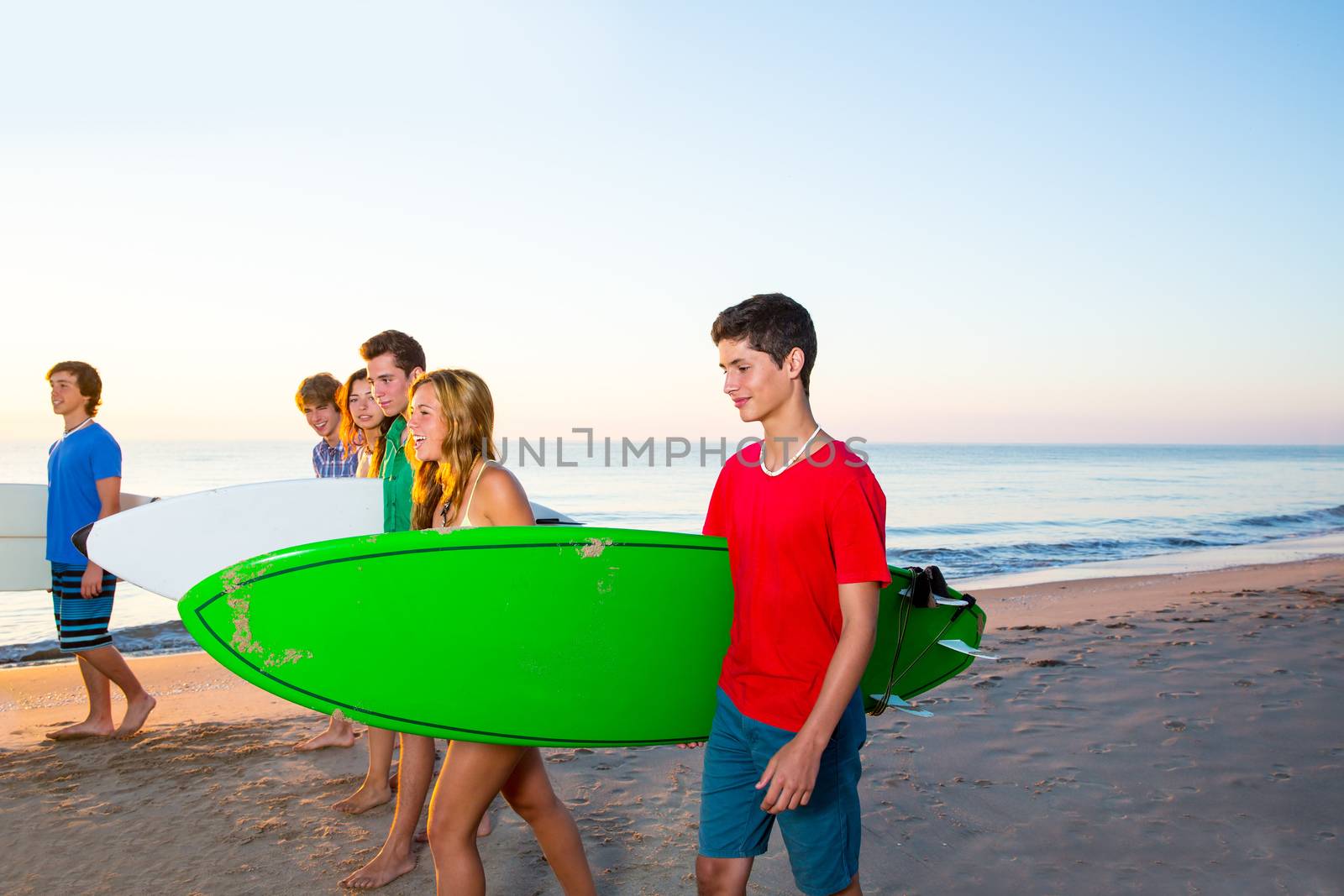 Surfer teen boys girls group walking on beach by lunamarina