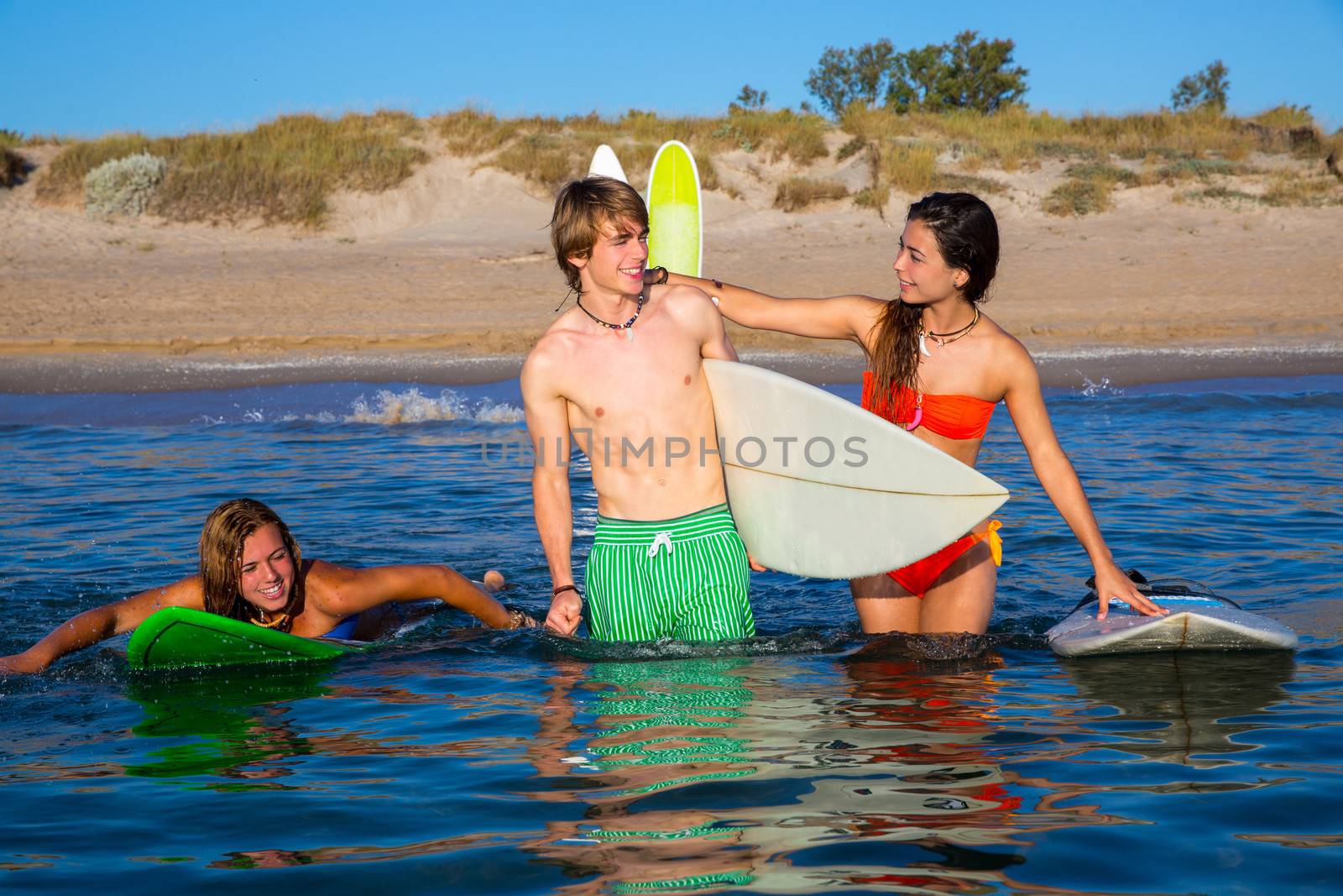 Happy teen surfers talking on beach shore by lunamarina