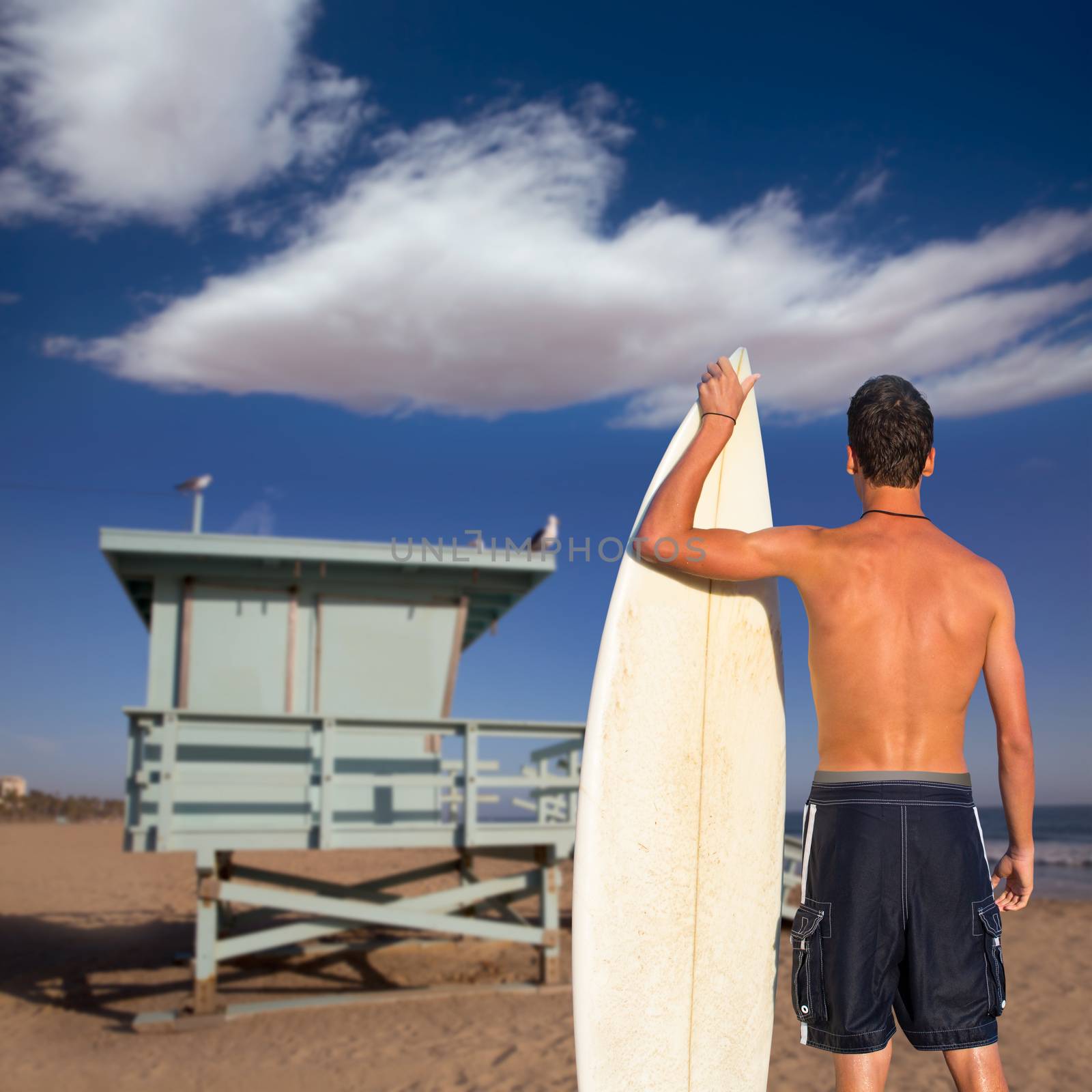 Boy surfer back view holding surfboard on beach by lunamarina