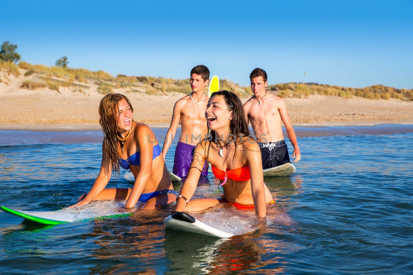 Teenager surfer boys and girls swimming ove surfboard by lunamarina