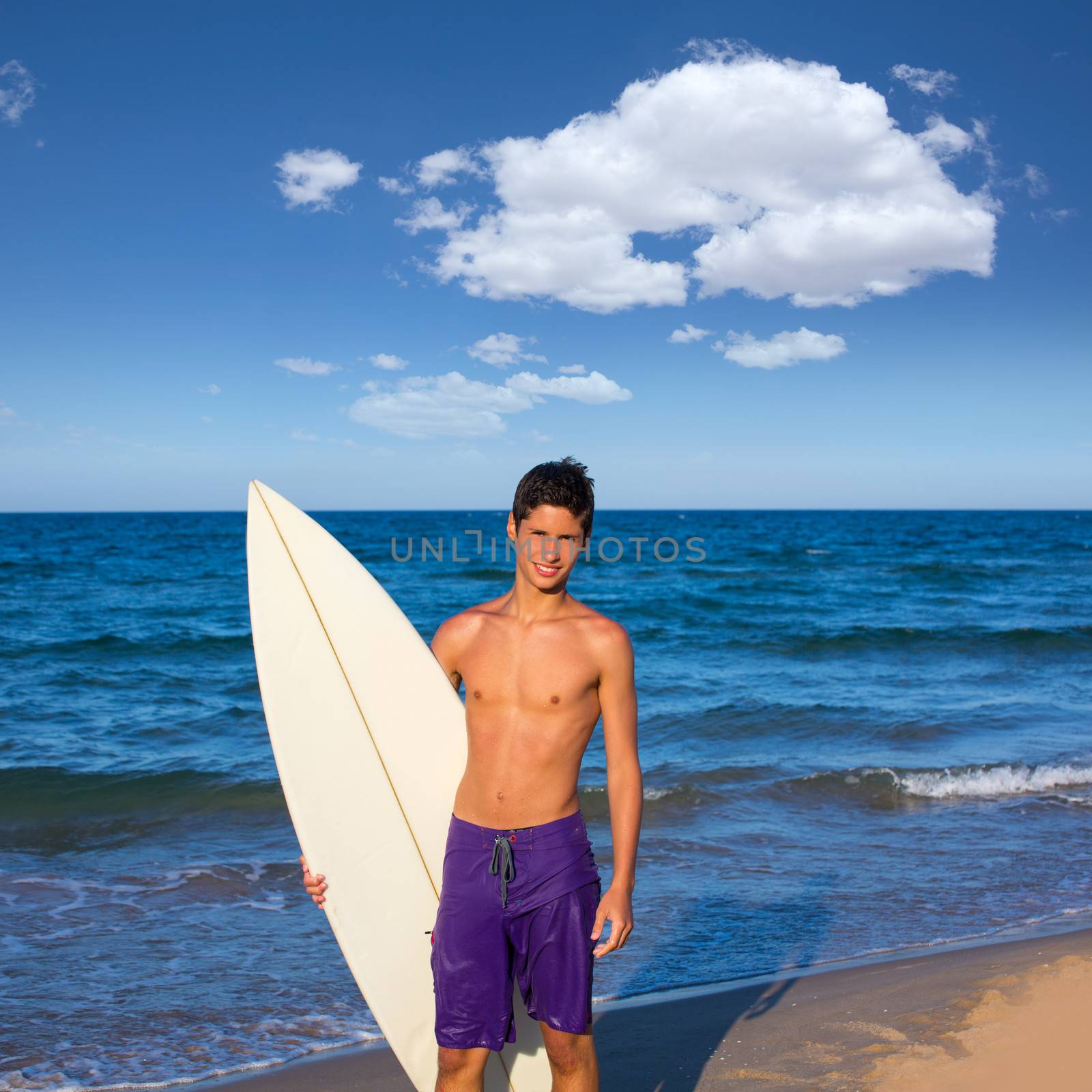 Boy teen surfer happy holing surfboard on the beach by lunamarina