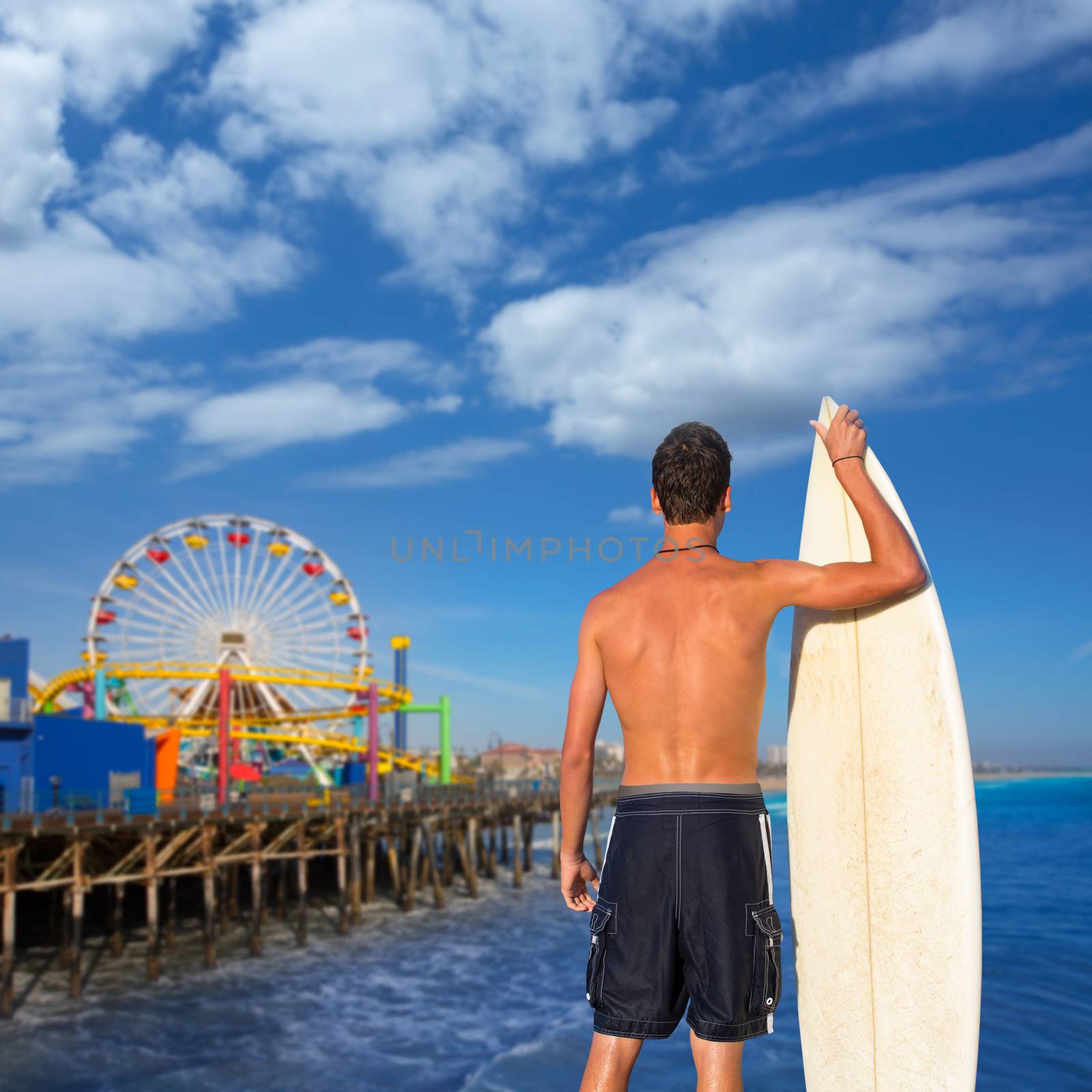 Boy surfer back rear view holding surfboard on santa Monica Pier California