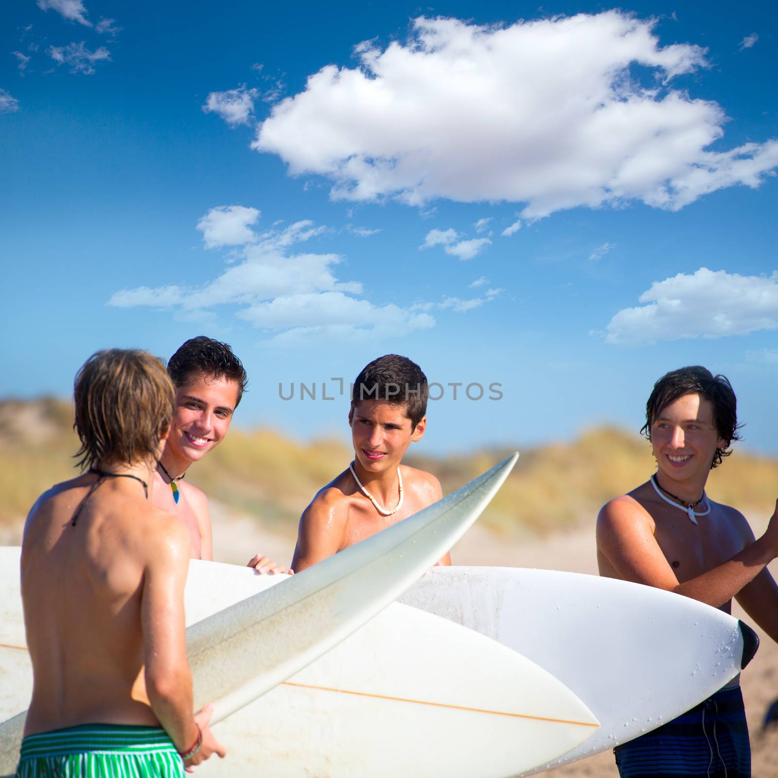 Surfer teen boys talking on beach shore holding surfboards