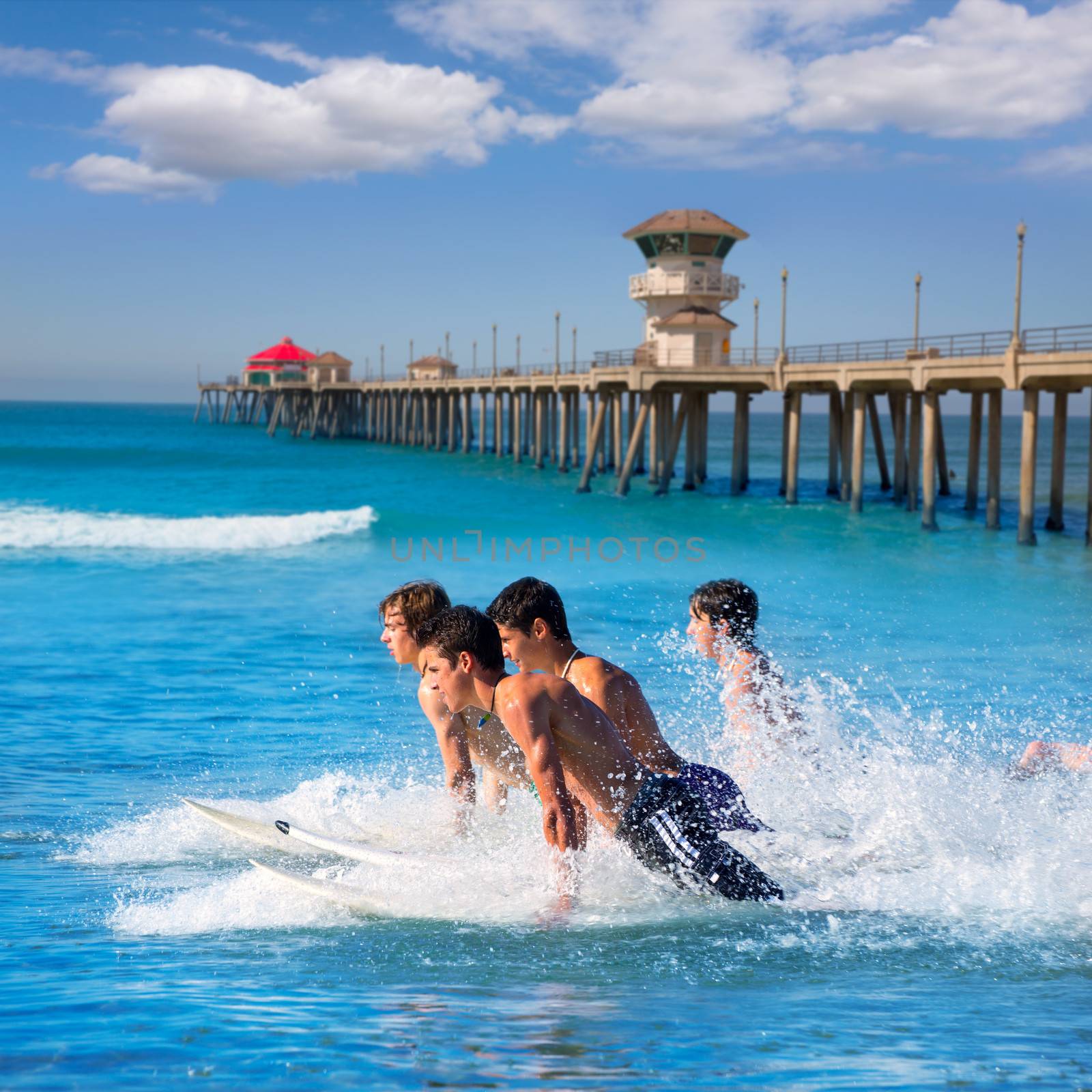 Teenager surfers surfing running jumping on surfboards at Huntinton beach pier California