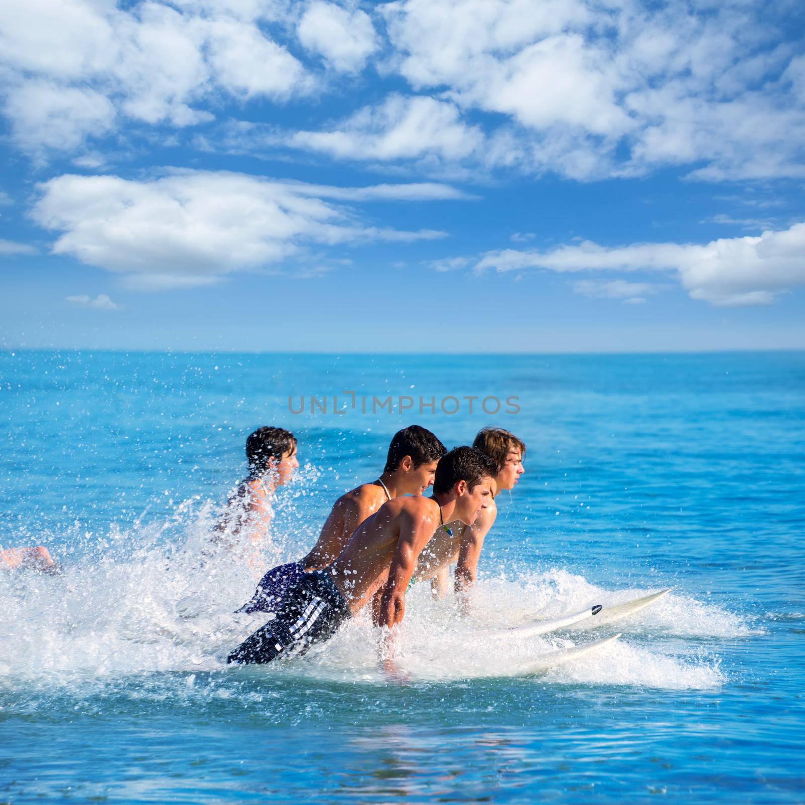 Boys teen surfers surfing running jumping on surfboards at the beach