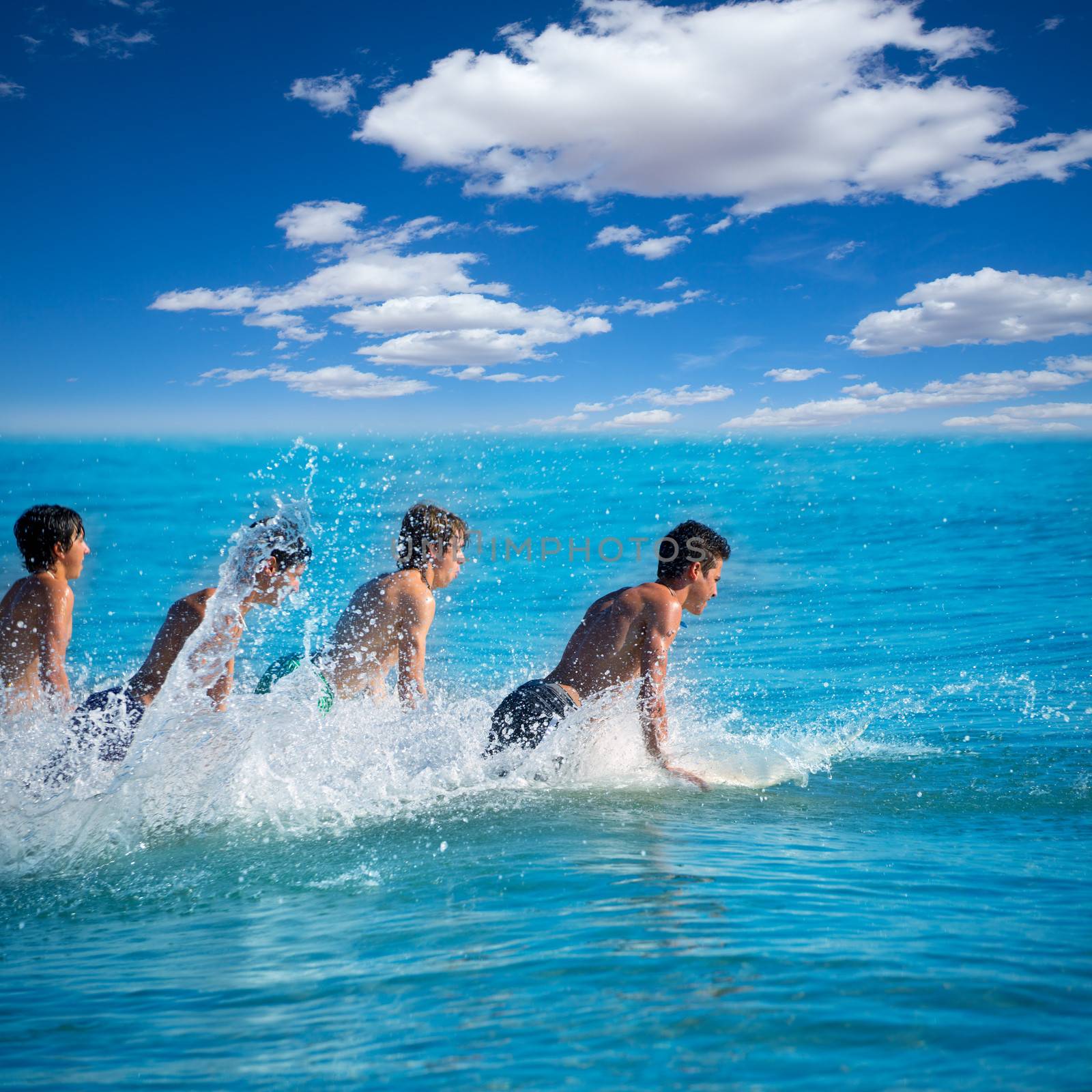 Boys teen surfers surfing running jumping on surfboards at the beach