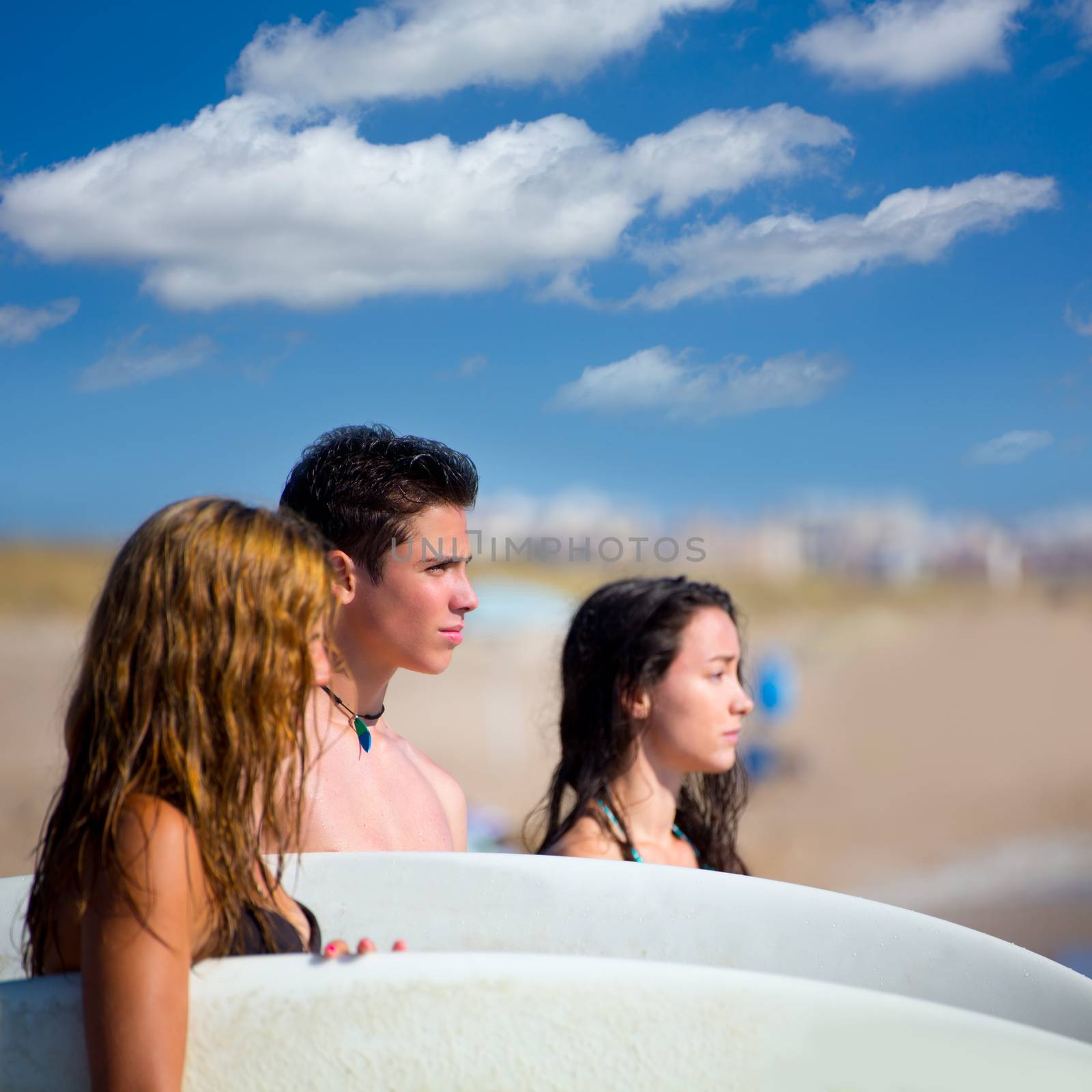 Teenager surfers group happy in beach shore by lunamarina