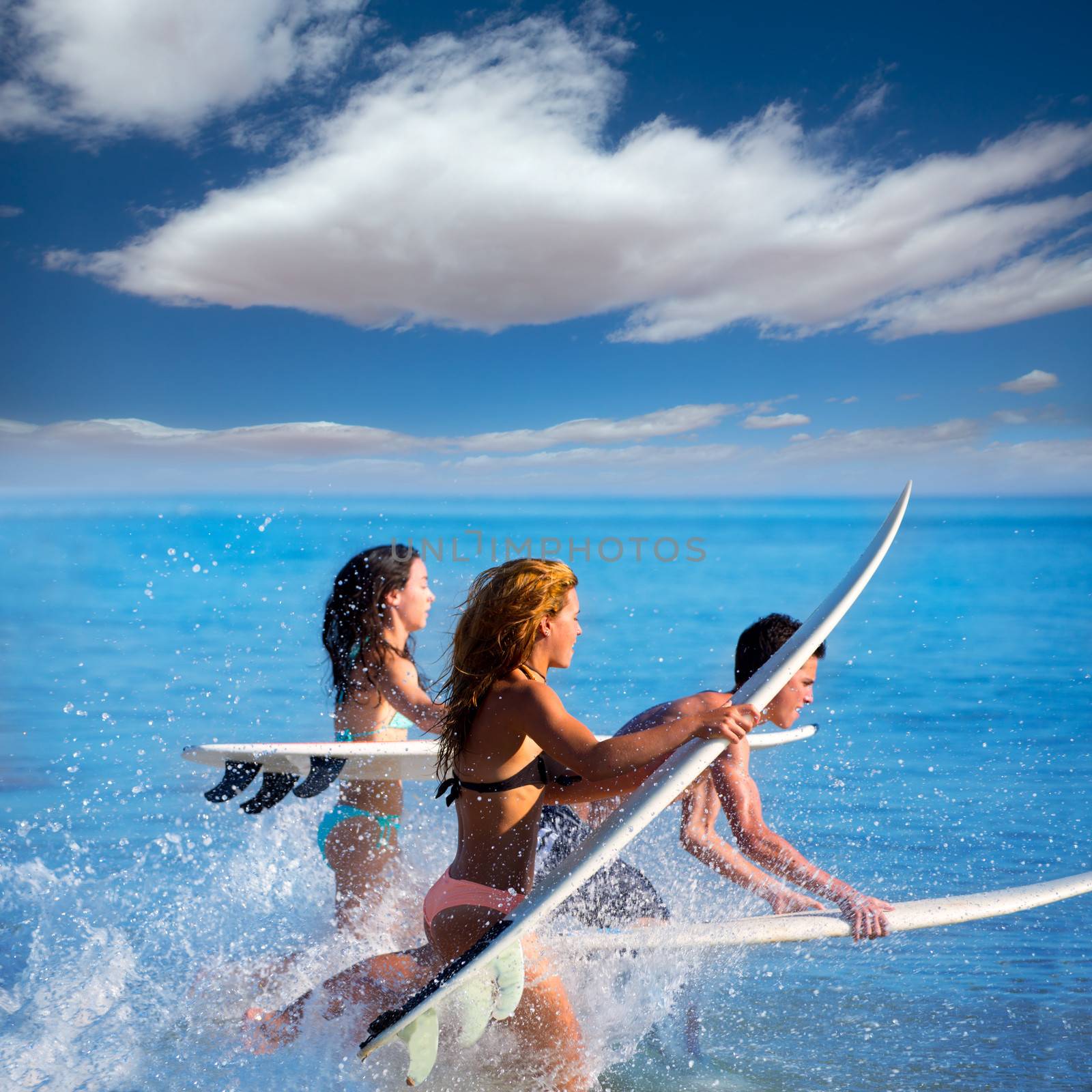 Boys and girls teen surfers running jumping on surfboards by lunamarina