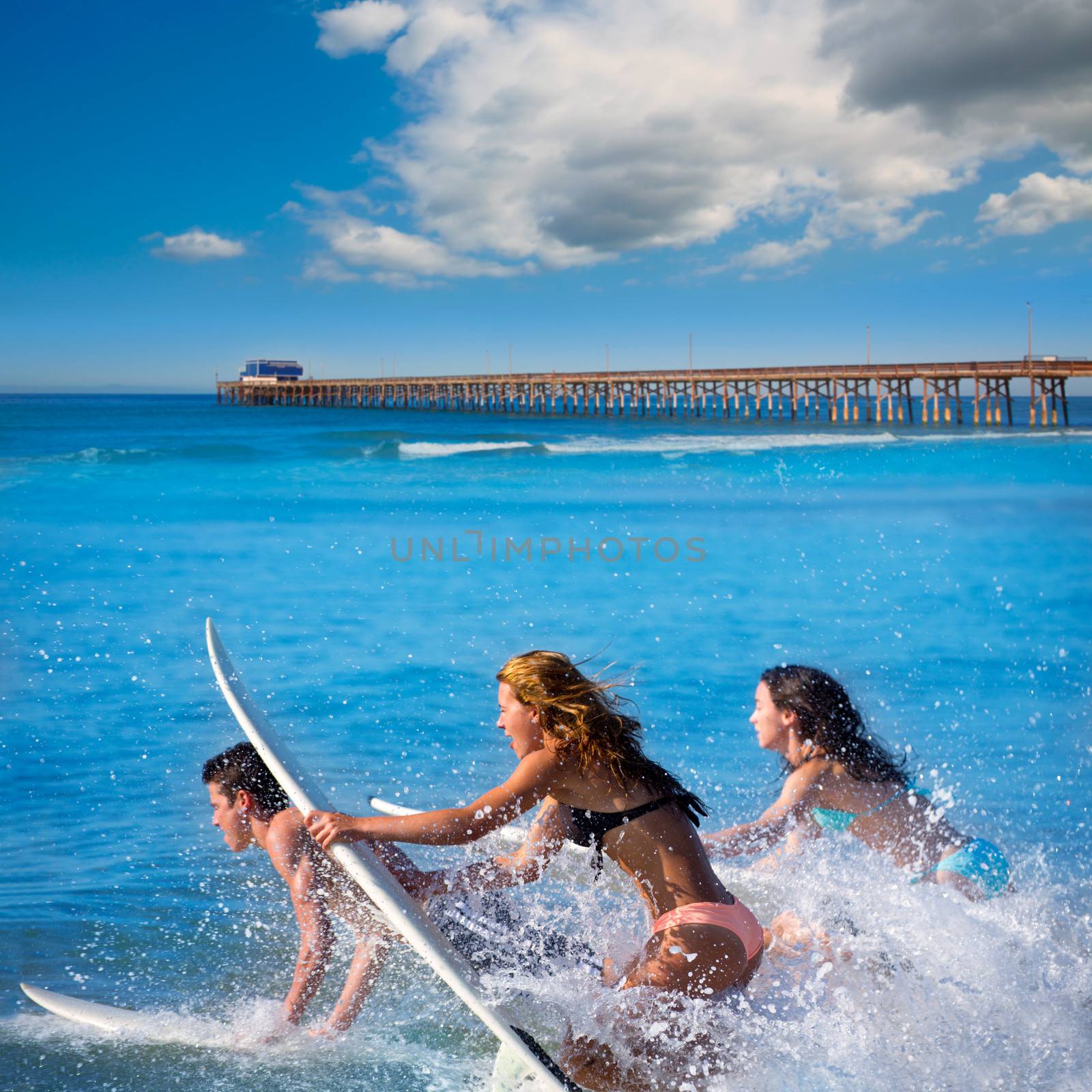 Teenager surfers surfing running jumping on surfboards at Newport pier beach California