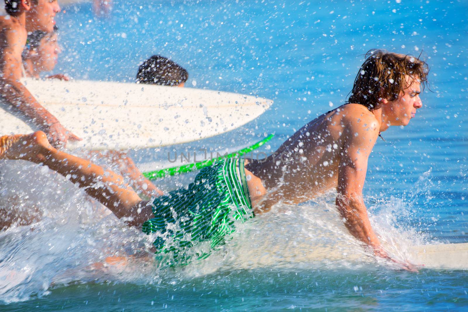 Boys teen surfers surfing running jumping on surfboards at the beach