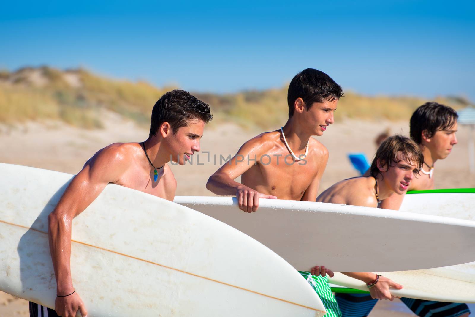 Surfer teen boys talking on beach shore holding surfboards