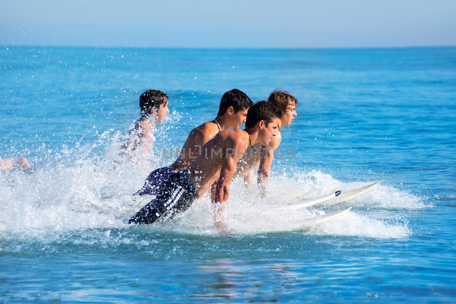 Boys teen surfers surfing running jumping on surfboards at the beach