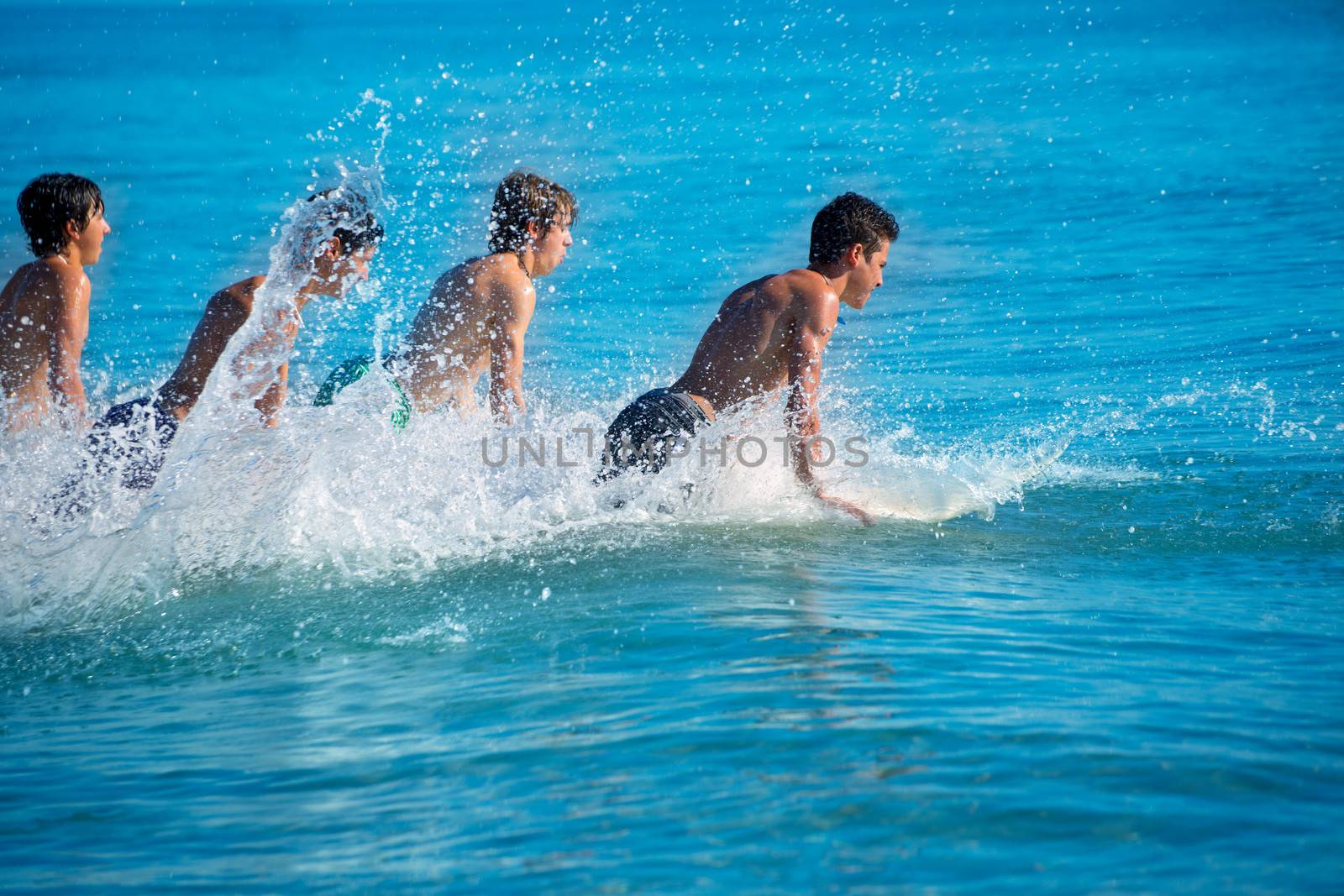 Boys teen surfers surfing running jumping on surfboards at the beach